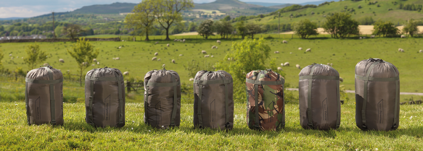 Variety of sleeping bags against a background of sheep fields. 