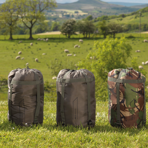 Variety of sleeping bags against a background of sheep fields. 